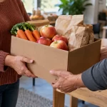 Dos personas entregando una caja de alimentos en un espacio comunitario.