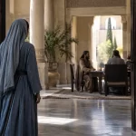 Recreación de una mujer ante la entrada de una sala palaciega antigua.